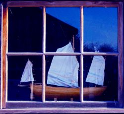 Model sailing ship seen through wood-framed window